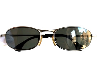 May include: Silver aviator sunglasses with dark gray lenses. The sunglasses have a classic oval shape and a thin metal frame.