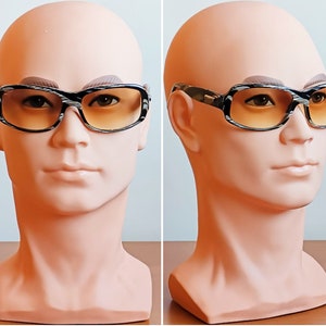Puede incluir: Gafas de sol rectangulares con montura estampada en blanco y negro y lentes degradadas en naranja. Las gafas se exhiben en una cabeza de maniqu&iacute;. Las monturas tienen un aspecto texturizado y las lentes pasan de un naranja m&aacute;s oscuro en la parte superior a un tono m&aacute;s claro.