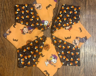 Puede incluir: Una decoración de Halloween en forma de estrella hecha de tela. La decoración presenta paneles naranjas y negros alternados. Los paneles naranjas tienen personajes de dibujos animados y murciélagos, mientras que los paneles negros tienen caramelos de maíz.