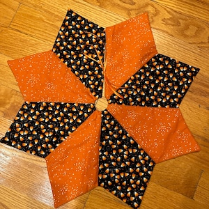 Può includere: Una gonna per albero di Natale a forma di stella di colore arancione e nero con un motivo a mais dolce. La gonna è realizzata in tessuto con una finitura scintillante.