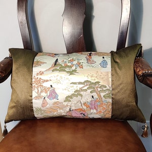 May include: A green and gold throw pillow with a Japanese-inspired design featuring figures in traditional clothing and a floral pattern.