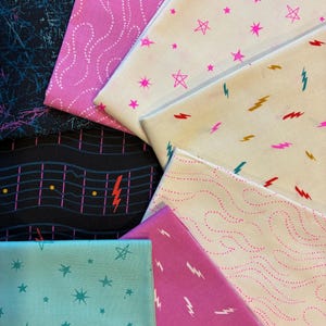 Puede incluir: Una colección de piezas de tela dobladas con varios patrones. Los diseños incluyen estrellas rosas, rayos y líneas punteadas sobre fondos blancos y rosas. Otras telas presentan estrellas turquesas y una cuadrícula negra con rayos.