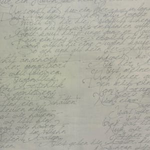 May include: A light gray fabric with handwritten script in a darker gray ink. The script appears to be in German, with elegant cursive lettering covering the entire surface. The fabric is likely used for crafting or decorative purposes.