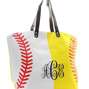 May include: A baseball-themed tote bag with a white and yellow design. The bag features red stitching details and a black monogram. It has brown handles and is designed to resemble a baseball.