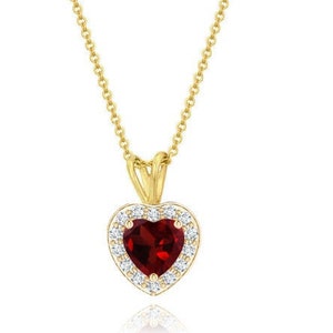 Peut inclure: Un collier avec un pendentif en forme de cœur en or, orné d'une pierre précieuse rouge entourée d'un halo de petites pierres blanches.