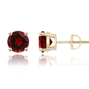 May include: A pair of gold stud earrings with round red garnet gemstones.