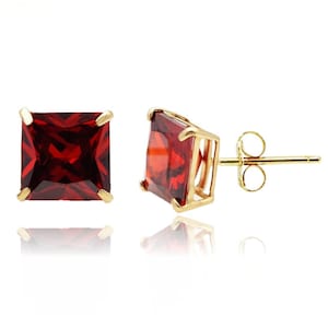May include: A pair of gold earrings with square red gemstone studs.