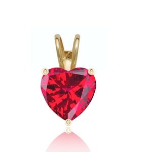 May include: A gold heart-shaped pendant with a red gemstone.