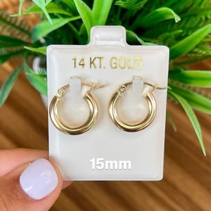 Puede incluir: Un par de pendientes de aro de oro de 14 quilates en una tarjeta blanca con el texto "14 KT. GOLD" y "15mm". Los pendientes tienen un di&aacute;metro de 15 mil&iacute;metros.