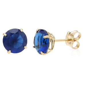 May include: A pair of gold stud earrings with a round blue gemstone in each earring.