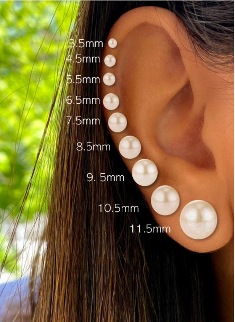 May include: Close-up of an ear with a series of pearl stud earrings in graduated sizes, ranging from 3.5mm to 11.5mm. The earrings are white and round, displayed against the skin. The image includes size labels.