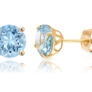May include: A pair of gold earrings with round blue topaz gemstones. The earrings have a simple post back.
