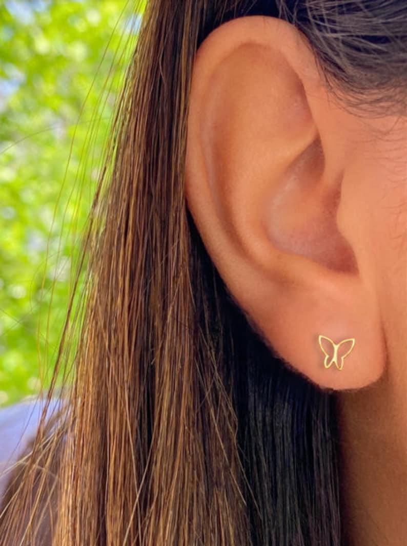K&ouml;nnte beinhalten: Ein Paar goldene Schmetterlings-Ohrstecker. Die Ohrringe sind klein und zart und perfekt, um jedem Outfit einen Hauch von Eleganz zu verleihen.