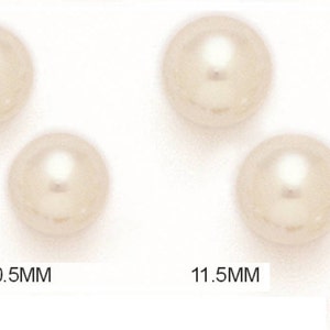 May include: Four cream-colored, round pearls are displayed. Two pearls measure 10.5mm, and the other two measure 11.5mm. The pearls have a glossy finish and a subtle, reflective sheen, suggesting their high quality. The image is well-lit, highlighting the pearls' smooth surfaces.