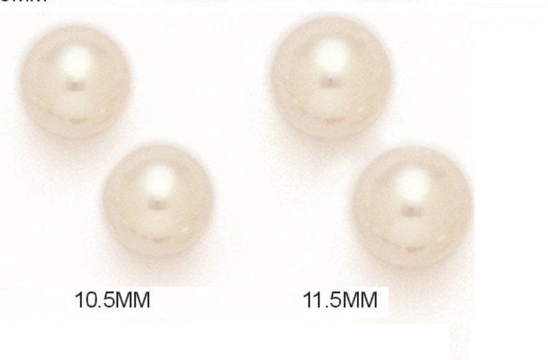 May include: Four cream-colored, round pearls are displayed. Two pearls measure 10.5mm, and the other two measure 11.5mm. The pearls have a glossy finish and a subtle, reflective sheen, suggesting their high quality. The image is well-lit, highlighting the pearls' smooth surfaces.
