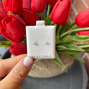 K&ouml;nnte beinhalten: Ein Paar kleine goldene Schmetterlings-Ohrringe auf einer wei&szlig;en Karte mit dem Text "14 KT. GOLD".