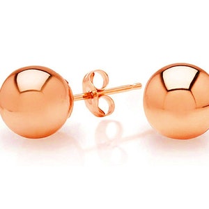 Könnte beinhalten: Ein Paar Ohrstecker aus Roségold mit runden, kugelförmigen Stiften.