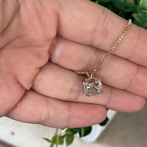 May include: A gold chain necklace with a square-shaped pendant featuring a clear gemstone. The pendant has the inscription "14K" on the back.