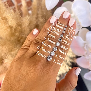 May include: A hand model wearing a ring with a diamond on each finger. The diamonds are arranged in a line from smallest to largest, with the smallest diamond being 3mm and the largest diamond being 7mm. The diamonds are labeled with their size in millimeters and their carat weight.