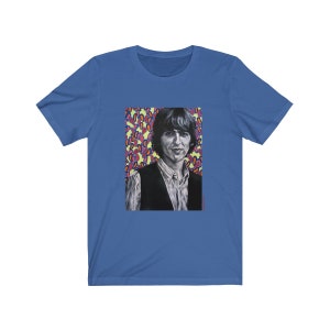 Puede incluir: Una camiseta azul con un gr&aacute;fico de un hombre con cabello oscuro y un chaleco negro. El fondo del gr&aacute;fico es un patr&oacute;n colorido de rosa, amarillo y azul.