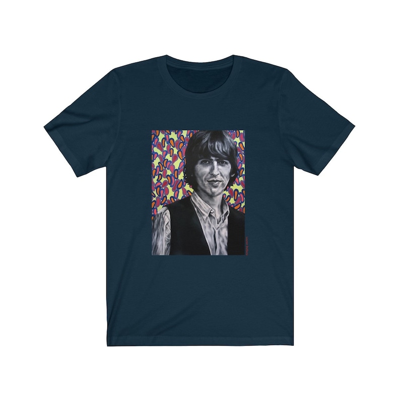 Puede incluir: Una camiseta azul marino con un estampado gr&aacute;fico de un hombre con cabello oscuro y un chaleco negro. El fondo del gr&aacute;fico es un patr&oacute;n abstracto amarillo, rosa y azul.