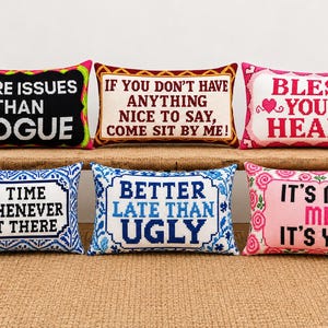 May include: Six rectangular needlepoint pillows featuring various phrases: MORE ISSUES THAN VOGUE, IF YOU DON'T HAVE ANYTHING NICE TO SAY, COME SIT BY ME!, BLESS YOUR HEART, ON TIME IS WHENEVER I GET THERE, BETTER LATE THAN UGLY, and IT'S NOT ME IT'S YOU.