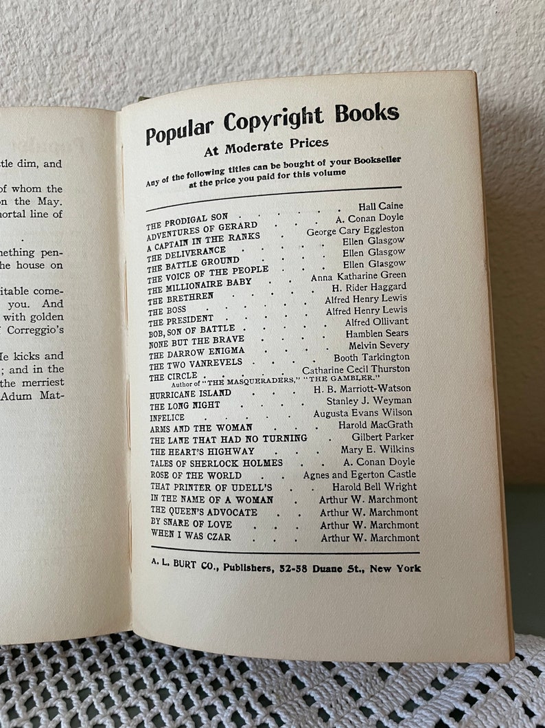 May include: Open book page with a list of titles from "Popular Copyright Books" at moderate prices. The titles and authors are listed in two columns. The book is open on a white surface.