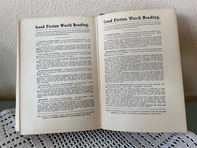 May include: Open book pages with text titled "Good Fiction Worth Reading." The text lists several book titles with descriptions. The pages are off-white with black text. The book is open on a light-colored surface.