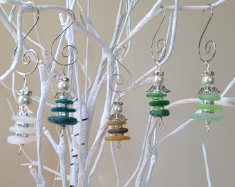 Pode incluir: Quatro enfeites de Natal feitos à mão com a forma de discos de vidro empilhados com detalhes prateados e uma pérola branca no topo. Os enfeites estão pendurados em um galho de bétula branco.
