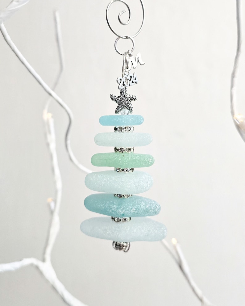 May include: Sea glass Christmas tree ornament with a starfish on top and a silver charm that says "2024".
