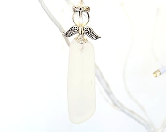 Pode incluir: Um ornamento de anjo de vidro do mar branco com asas prateadas e uma conta de cristal transparente. O ornamento está pendurado em um fio de prata.