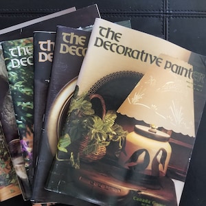 May include: A stack of vintage magazines titled "The Decorative Painter" with a brown and white lampshade on the cover of the top magazine.