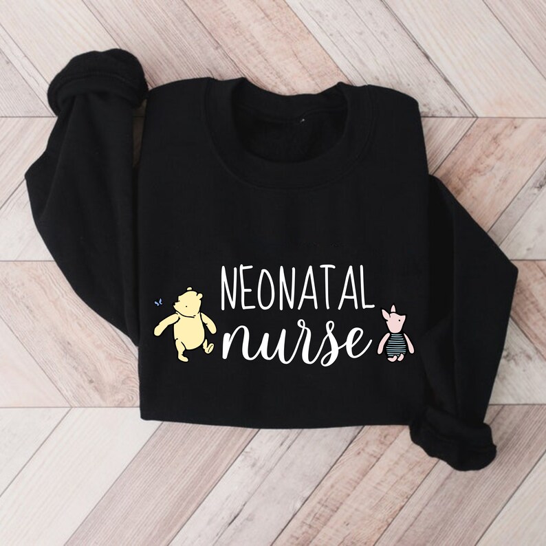 May include: Black sweatshirt with the text "NEONATAL nurse" in white lettering. A yellow cartoon bear and a pink cartoon pig are on either side of the text.
