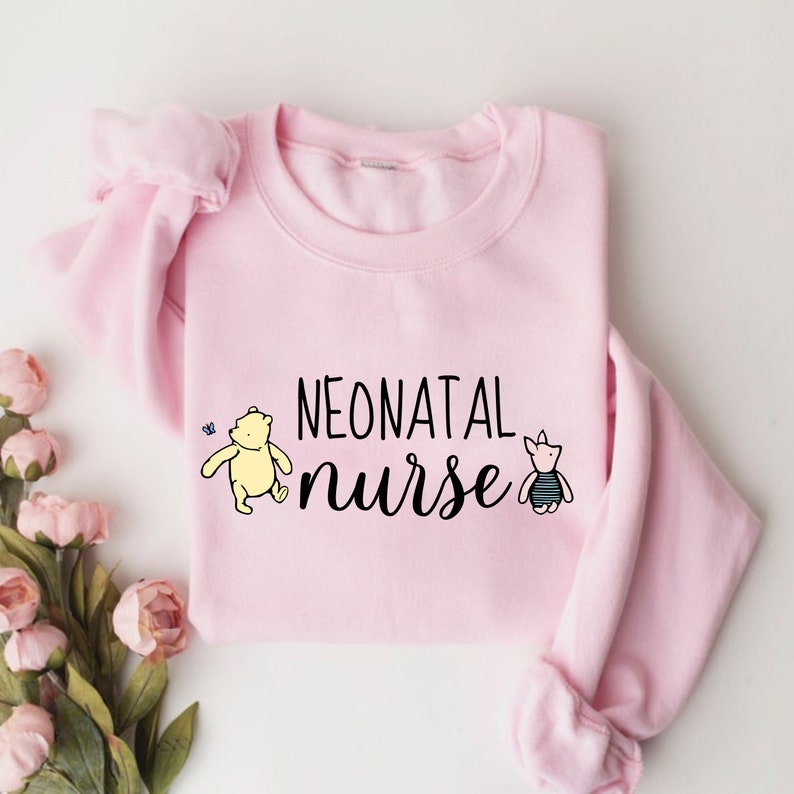 May include: Pink sweatshirt with the text "NEONATAL nurse" in black lettering. A cartoon Winnie the Pooh and Piglet are on either side of the text.