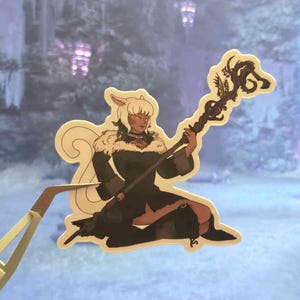 May include: A die-cut sticker featuring an illustrated character with light hair and cat-like ears, wearing a dark coat with a fur collar. The character is kneeling and holding a long, dark, twisted wooden staff topped with intricate, organic, branch-like designs.