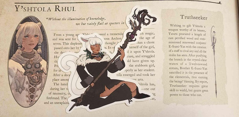 May include: A die-cut sticker featuring a character with white hair and cat-like ears, wearing a black outfit with a fur collar, holding a dark, ornate staff with a purple gem. The sticker is placed over a page of text titled Y'shtola Rhul.