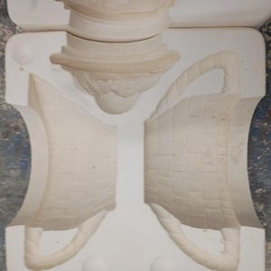May include: A white ceramic slip casting mold for a basket with a woven texture and a handle. The mold consists of two main side pieces and a separate top piece, all featuring recessed negative space to form the shape of a basket when cast.