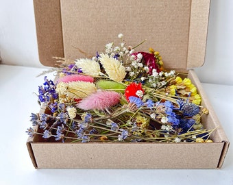 May include: A cardboard box filled with a variety of dried flowers, including lavender, pink, white, yellow, and blue flowers.