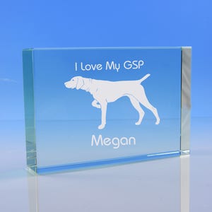 May include: A clear glass paperweight with a white silhouette of a German Shorthaired Pointer dog. The text "I love my GSP" and the name "Megan" are engraved on the paperweight.