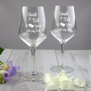 May include: Two clear glass wine glasses with the text "Sarah & Rob 40 Years 24th July 2018" etched on each.