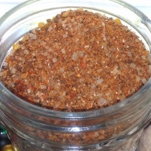 May include: A glass jar filled with a brown spice blend. The spice blend is made up of various ingredients, including salt, pepper, and herbs.