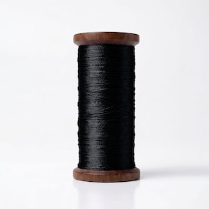 May include: A spool of black thread wound tightly around a cylindrical wooden core. The thread has a smooth, slightly reflective texture, and the spool features dark brown wooden ends at the top and bottom, providing a sturdy structure.