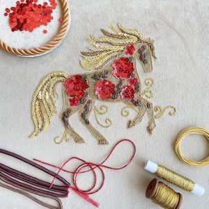 Puede incluir: Un diseño de caballo bordado con flores de lentejuelas rojas y detalles dorados. El caballo tiene una melena y cola fluidas, con remolinos decorativos. Se ven suministros de costura como lentejuelas rojas, hilo dorado y otros materiales.