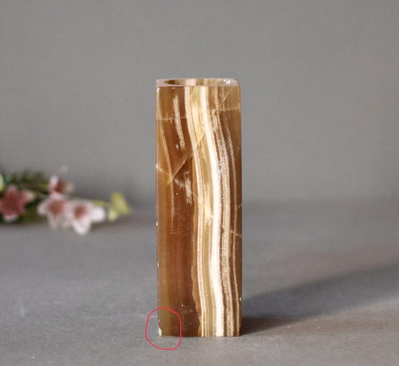 K&ouml;nnte beinhalten: Eine braune und wei&szlig;e gestreifte Onyx-Vase mit quadratischer Form. Die Vase ist aus Naturstein gefertigt und hat eine glatte, polierte Oberfl&auml;che.