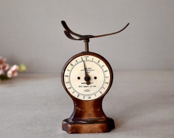 May include: A vintage Salter spring balance scale with a white face and black markings. The scale is made of metal and has a brown finish. The scale is marked "Salter Spring Balance 10 lb" and "Made in England 1000 Grams to 10 lbs".
