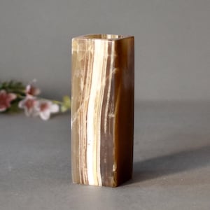 K&ouml;nnte beinhalten: Eine quadratische Onyx-Vase mit braunen und wei&szlig;en Streifen.