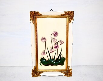 May include: A framed artwork featuring a 3D floral design with pink flowers and green leaves. The frame is white with gold accents.