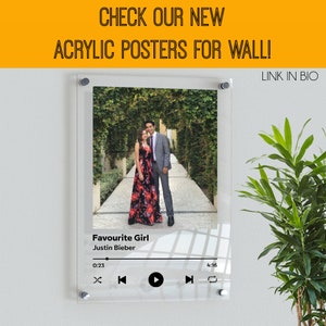 May include: A clear acrylic poster featuring a photograph of a couple in a garden setting. The poster has a music player design with the song title "Favourite Girl" by Justin Bieber.