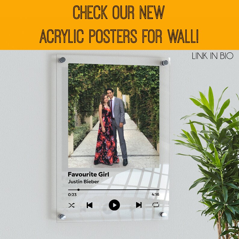 May include: A clear acrylic poster featuring a photograph of a couple in a garden setting. The poster has a music player design with the song title "Favourite Girl" by Justin Bieber.
