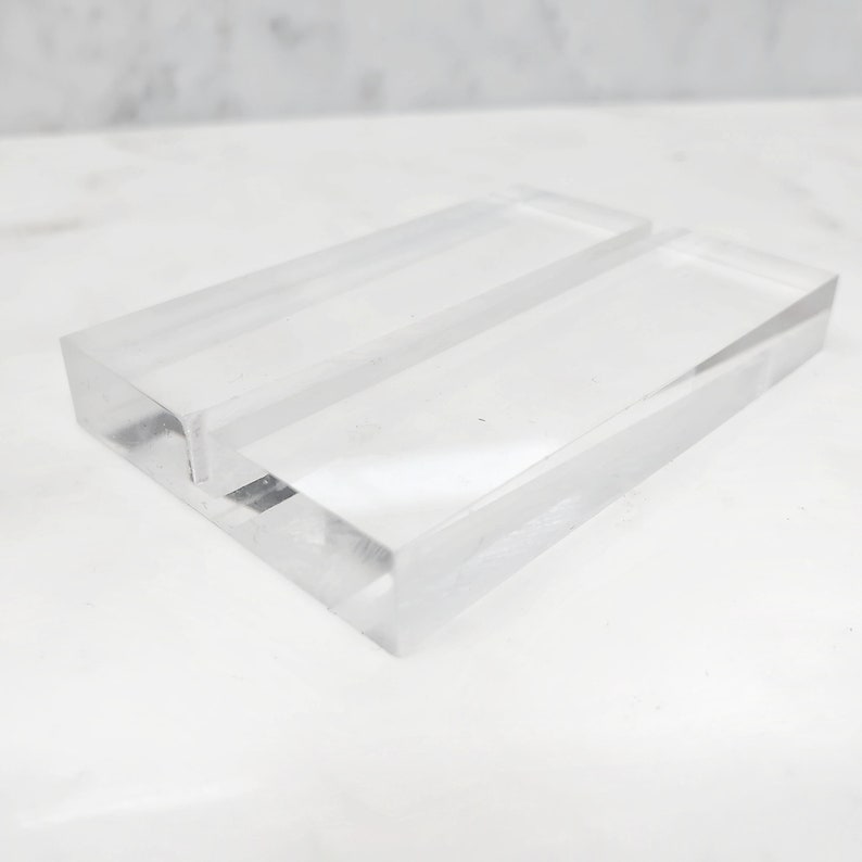 May include: A clear acrylic display stand with two slots for holding business cards or other small items.